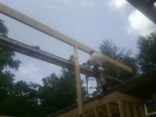 Carpenter setting a ridge beam over a new addition frame — Ice Dam Removal by Roofing Brothers in Iowa City