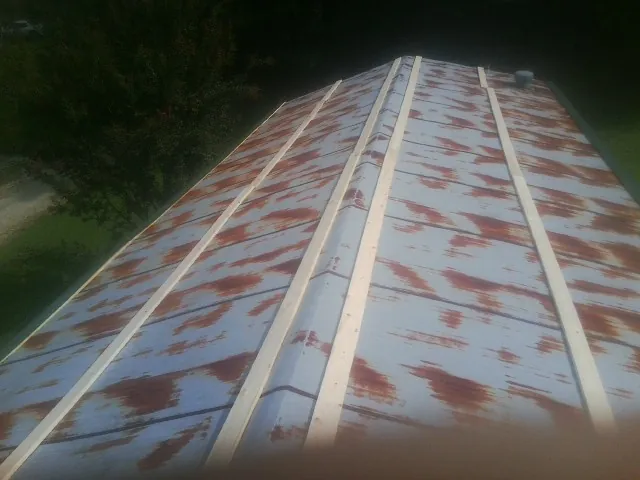 Rusted metal roof panels with new wood purlins before replacement — Storm Damage Roof Repair in Iowa City by Roofing Brothers