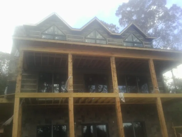 Dormers and porch framing on a large log home under construction — Roof Coating work by our crew in Iowa City