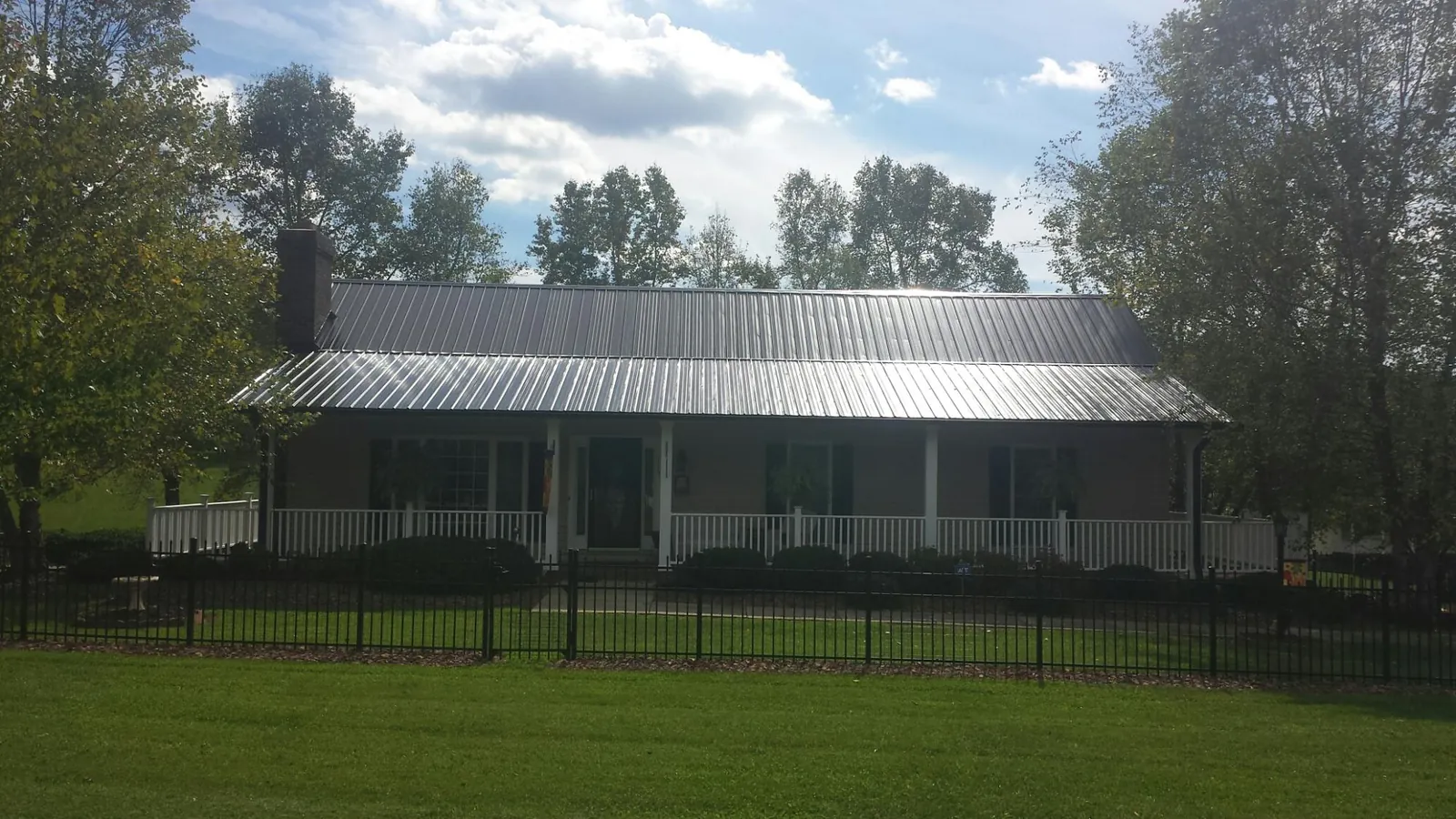 Gray metal roof on a brick ranch with a full width front porch — Gutter Guard Installation work by our crew in Iowa City