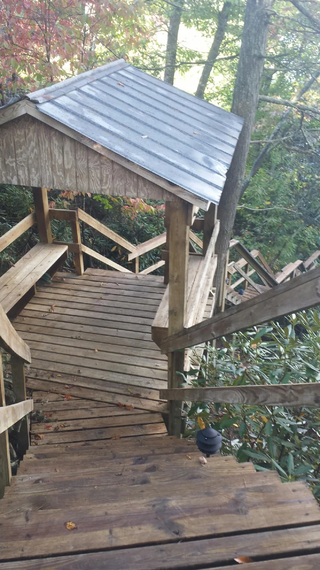 Metal roofed shelter over wooden steps on a wooded walkway — Skylight Repair & Installation work by our crew in Iowa City