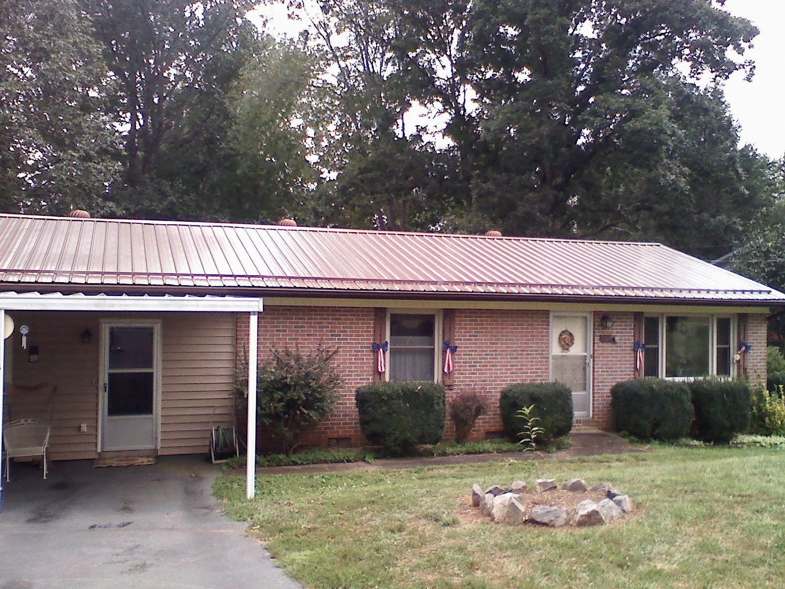 Bronze metal roof and carport on a brick ranch home — Roof Repair work by our crew in Iowa City
